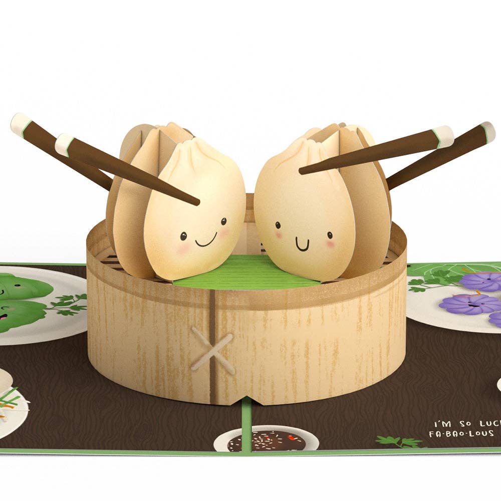 Two smiling dumplings in a paper steamer holding chopsticks