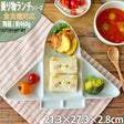 Children's lunch set with sandwich, vegetables, and soup on a wooden table.